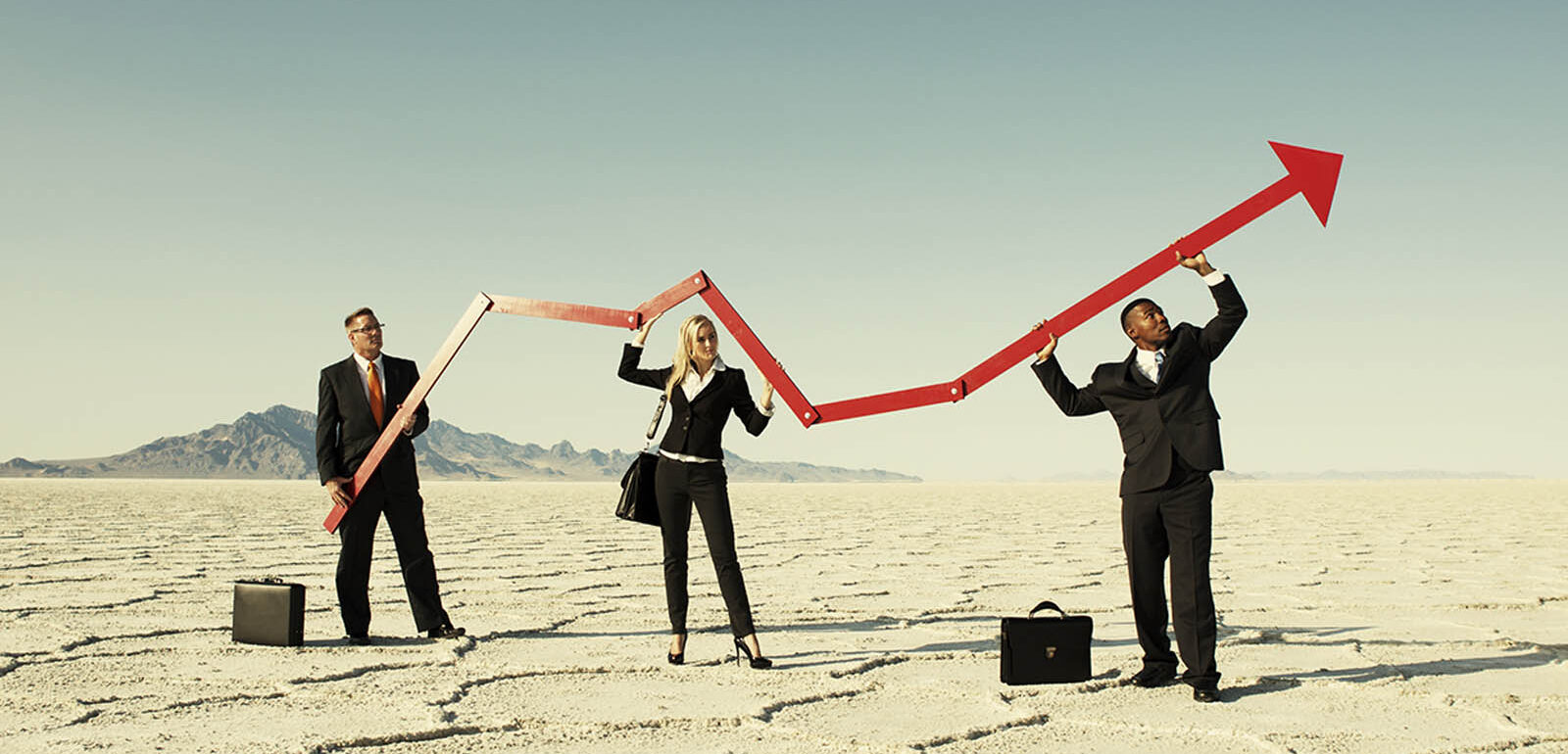 Business people holding up an arrow in the desert